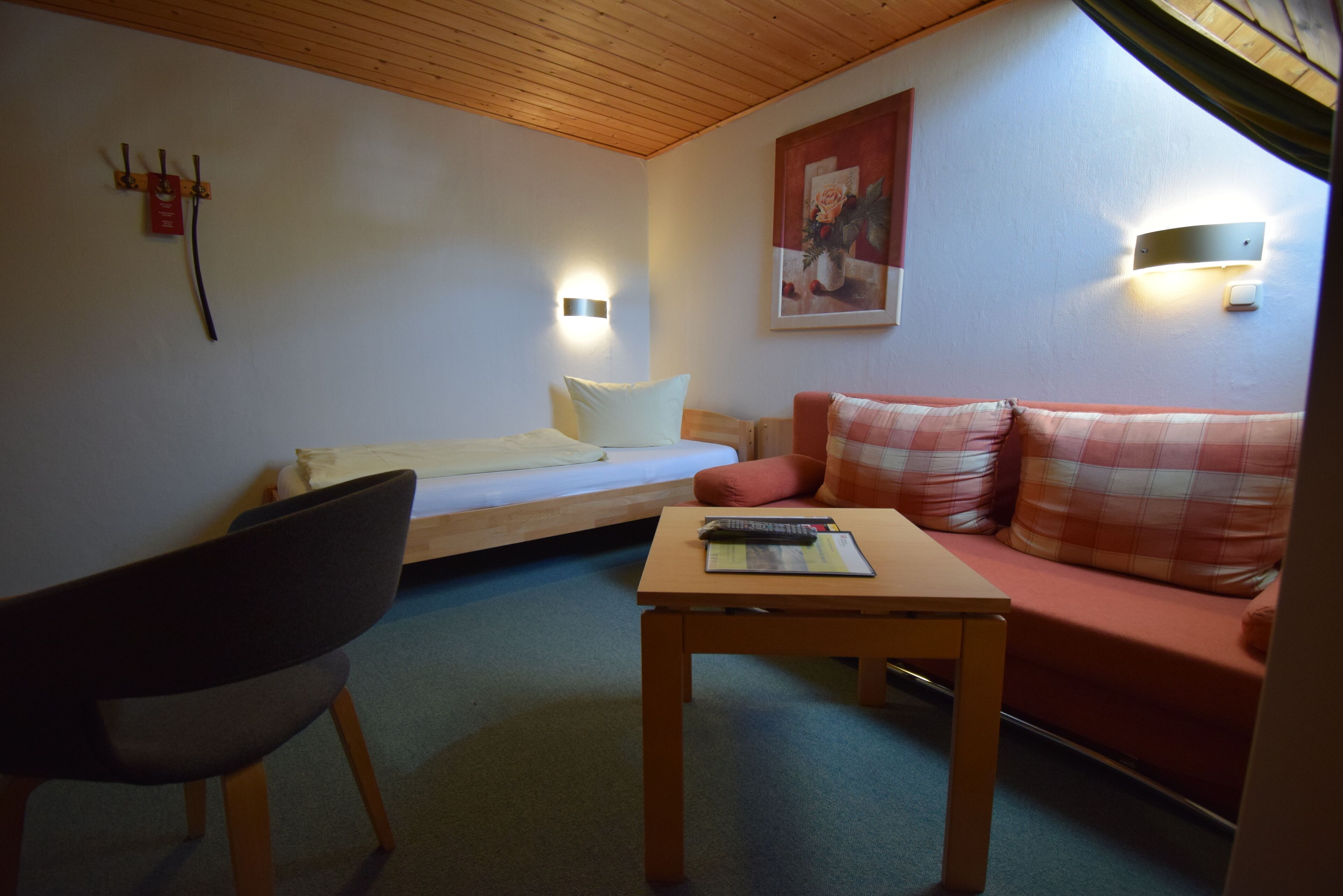 A cozy room with a bed, a sofa, a small table, and a chair.