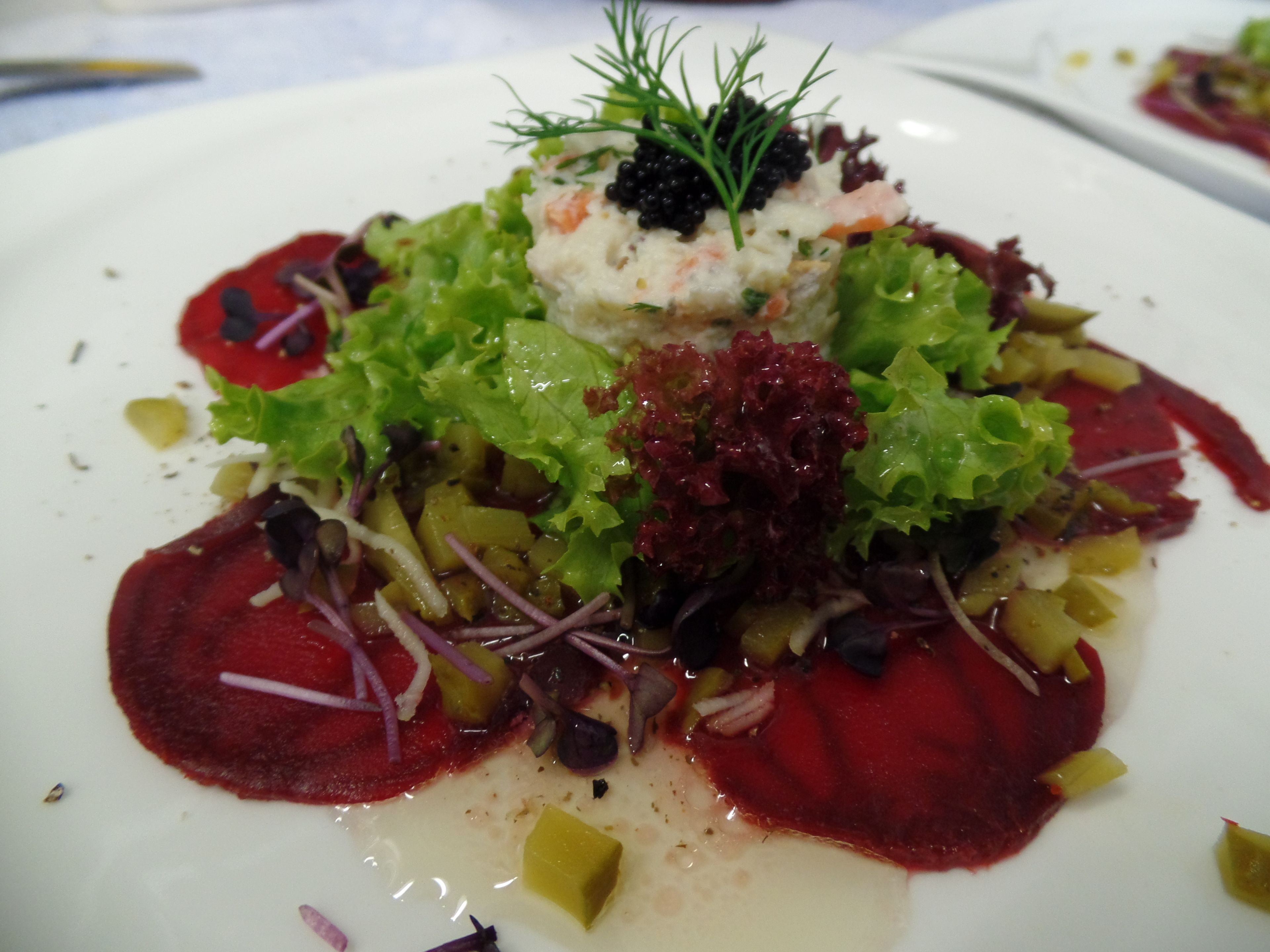 A plate of food with various vegetables and a dollop of cream in the center.