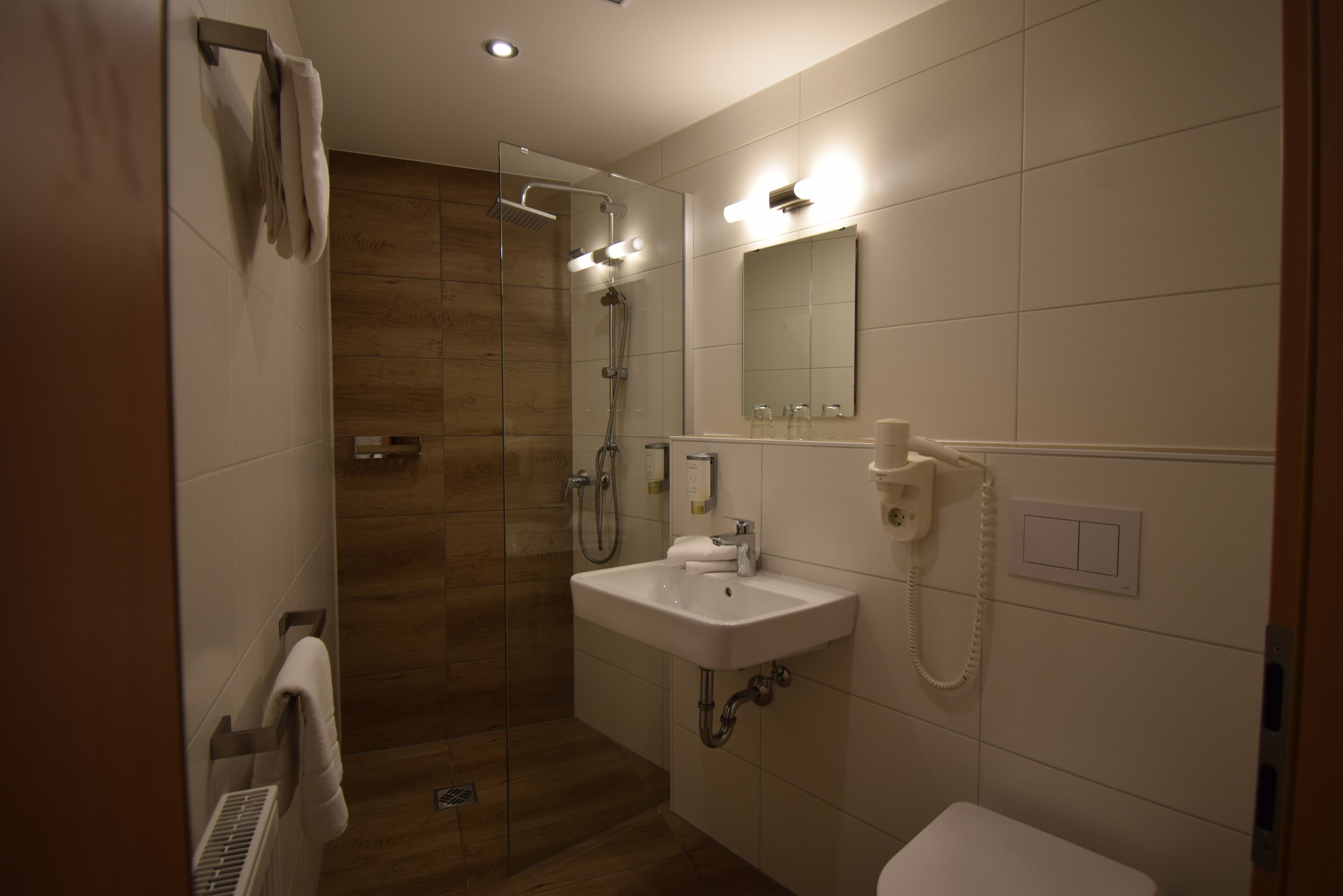 Un bagno moderno con doccia vetrata, lavandino bianco e specchio.
