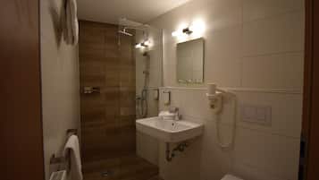 Un bagno moderno con doccia vetrata, lavandino bianco e specchio.