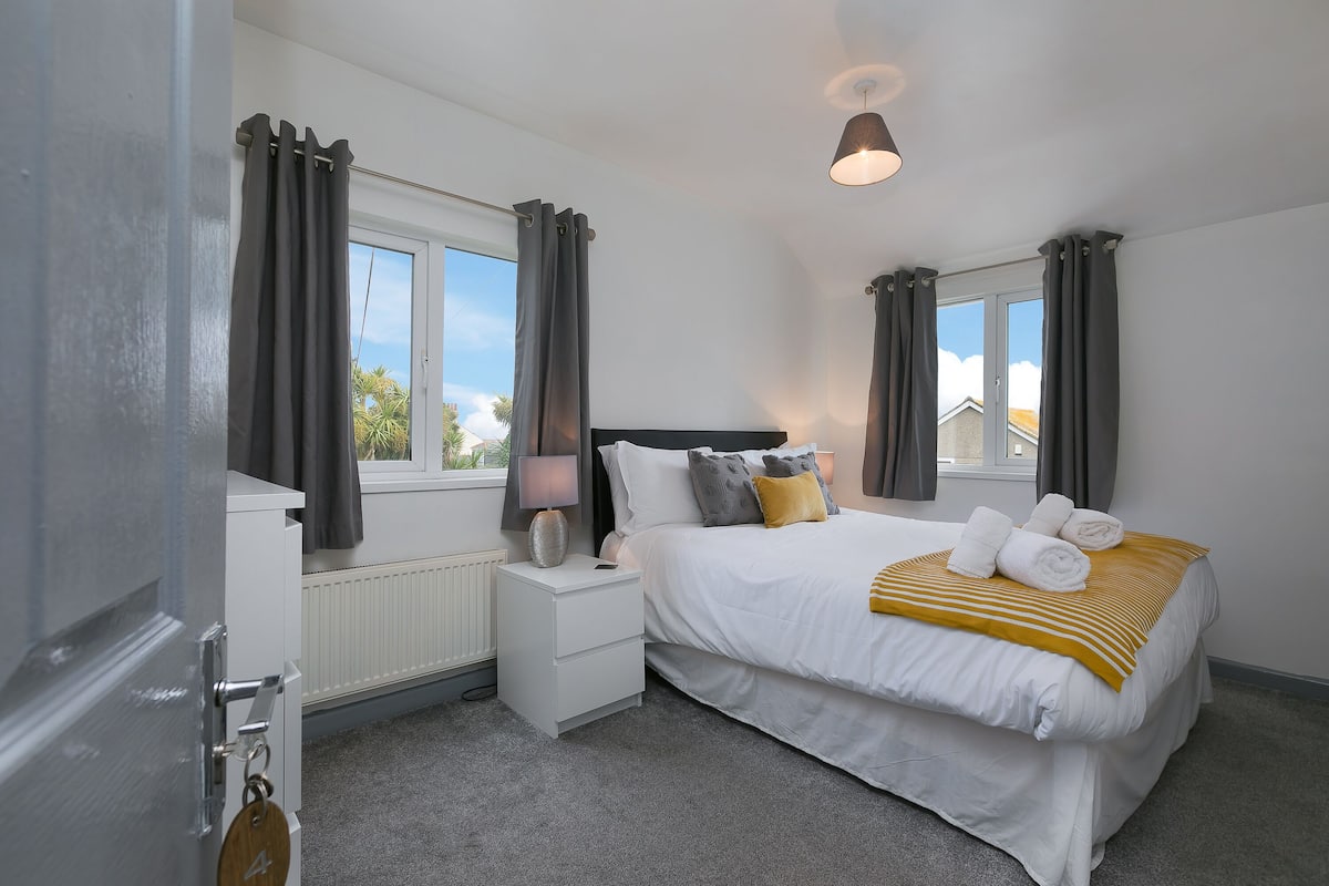 A bedroom with a bed, bedside tables, a lamp, and curtains.
