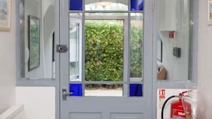 A grey door with a window, a fire extinguisher, and a framed picture on the wall. - The Nook (St Ives)