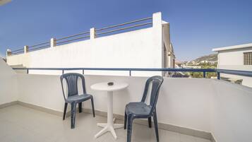 Un balcón con dos sillas y una mesa pequeña, con vistas a un paisaje urbano.