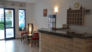 A hotel lobby with a reception desk, chairs, a clock, and a bulletin board. - Blue Roses (Rhodes)