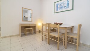 A small, clean room with a desk, two chairs, a mirror, and a framed picture on the wall. - Blue Roses (Rhodes)