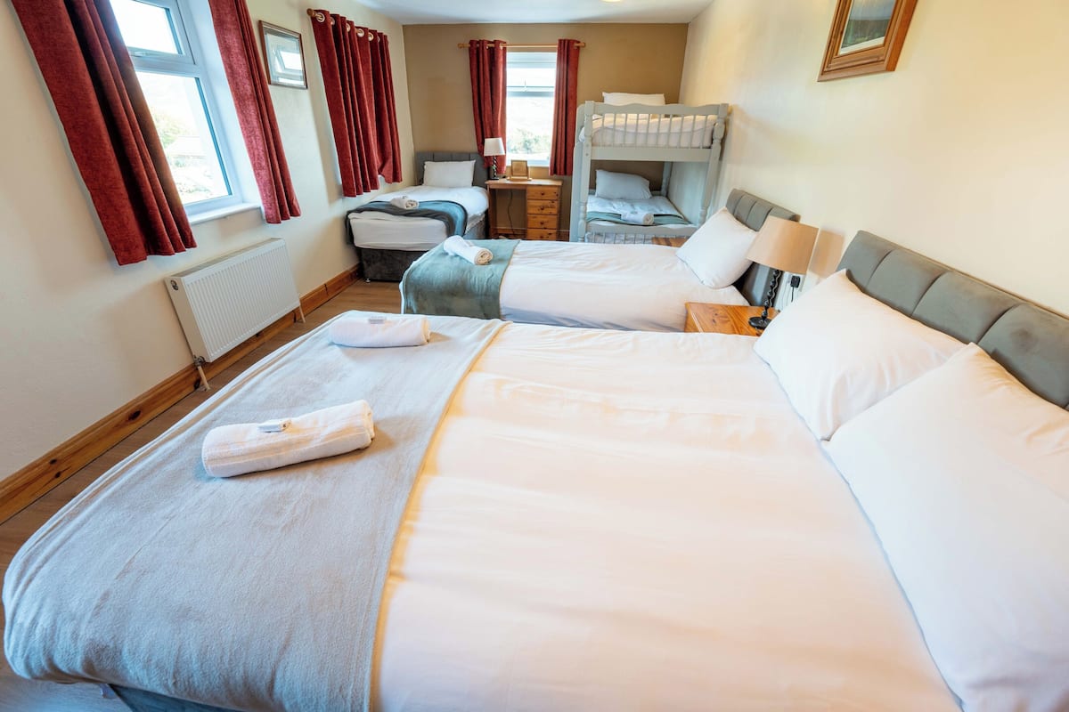 Une chambre d’hôtel avec deux lits, un bureau, un radiateur et une fenêtre avec des rideaux.