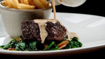 A steak with sauce and fries on a plate.