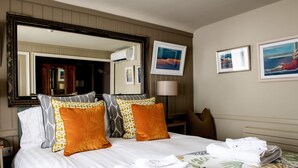 A neatly made bed with white linens and multiple pillows, a large mirror above it, and two framed pictures on the wall. - Marquis Of Granby (Dover)