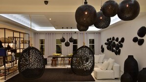 A modern living room with a white sofa, a dining table with chairs, and decorative wall art.