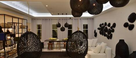 A modern living room with a white sofa, a dining table with chairs, and decorative wall art.
