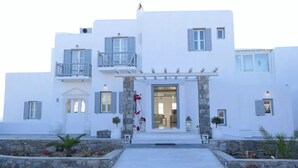 A white building with a stone entrance, balconies, and a covered porch.