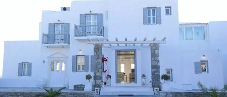 Un edificio blanco con entrada de piedra, balcones y un porche cubierto.