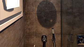 Une salle de bain moderne dotée d’une douche à parois de verre, d’un pommeau de douche à main et d’un robinet mural.