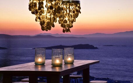 A wooden table with three lit candles and a hanging light fixture.