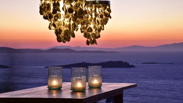 A wooden table with three lit candles and a hanging light fixture.