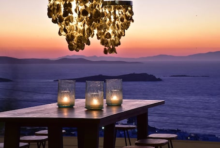 A wooden table with three lit candles and a hanging light fixture.