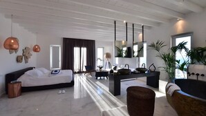 A modern living room with a large bed, a dining area, and a bathtub.