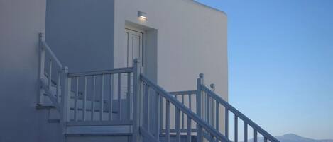 A modern building with a white exterior, a staircase with white railings, and a door.