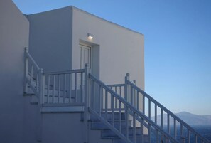 Un edificio moderno con fachada blanca, una escalera con barandillas blancas y una puerta.