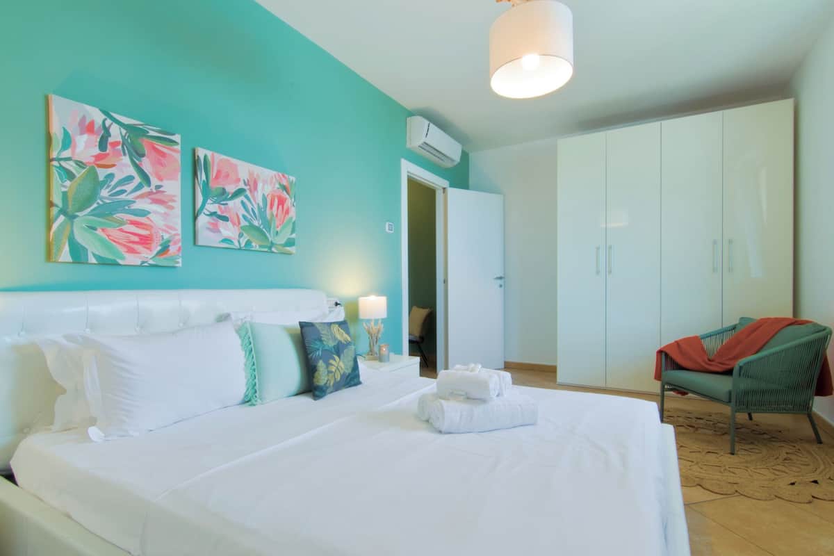 A hotel room with a large bed, a wardrobe, and two paintings on the wall.