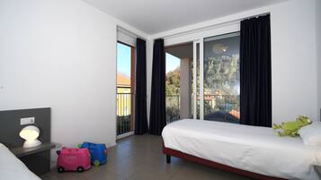 Cozy retreat with a large bed, bedside table, and balcony offering views of the surrounding cityscape.