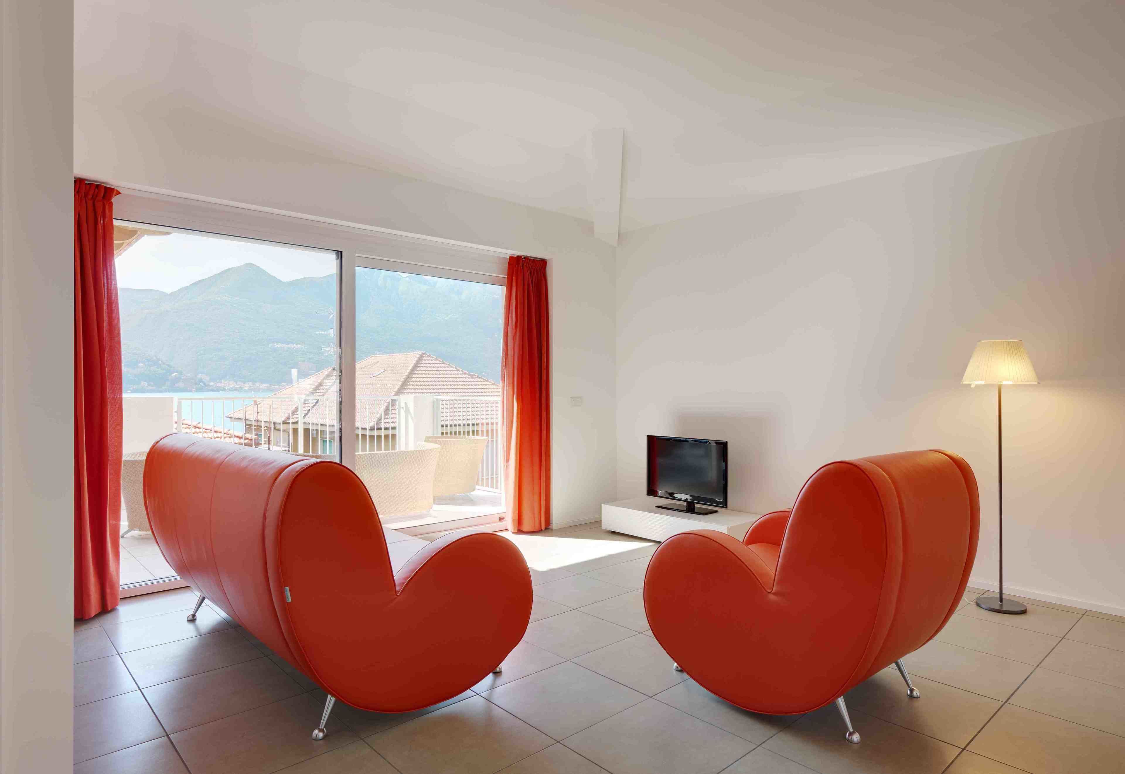 A modern room with two orange chairs, a TV, and a lamp.