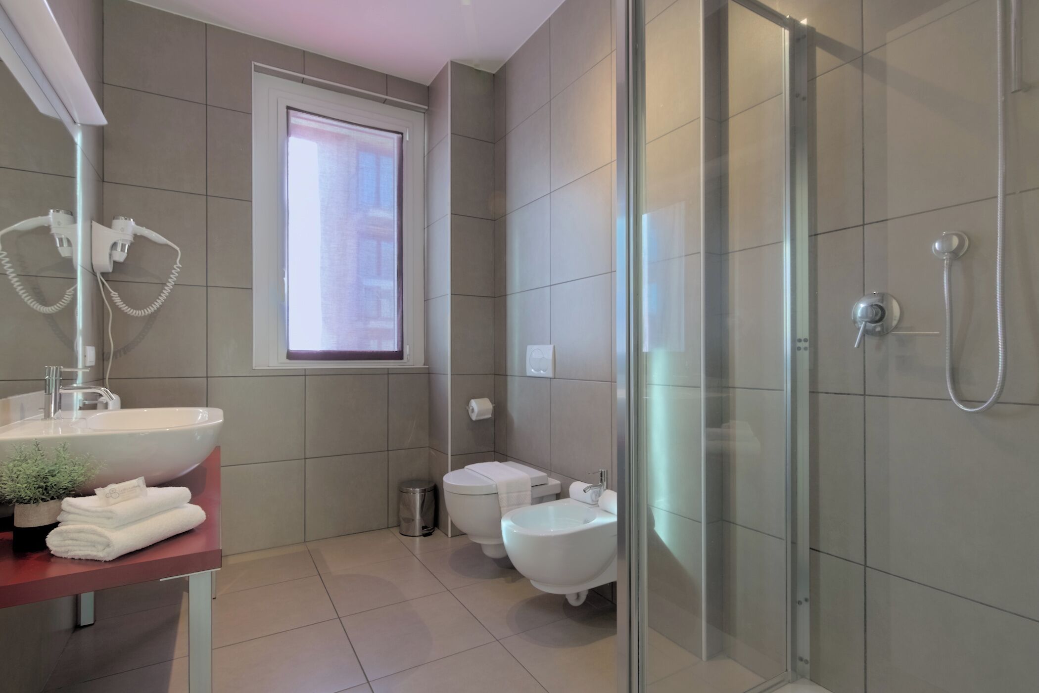 A modern bathroom with a glass-enclosed shower, a sink with a mirror, and a toilet.