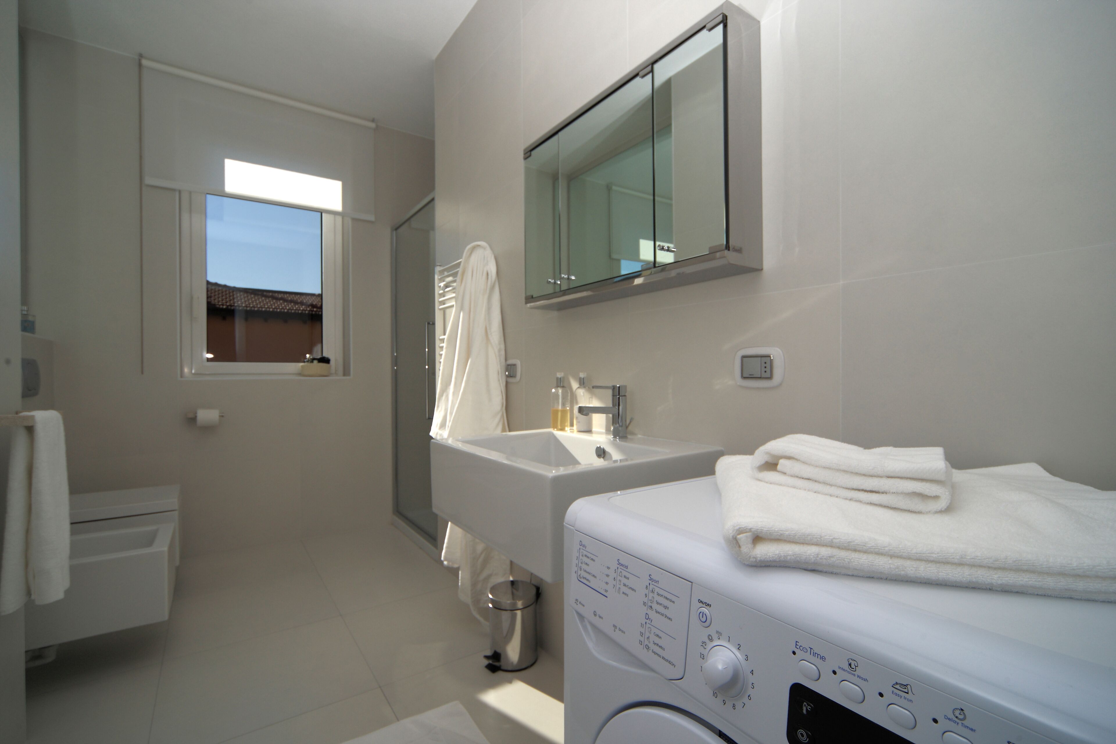 A modern bathroom with a built-in washing machine, a sink, and a mirror.