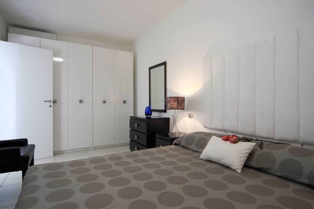 A bedroom with a bed, a dresser, a mirror, and a wardrobe.
