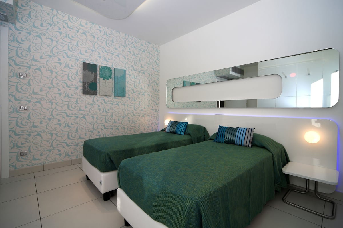 A room with two beds, a mirror, and a small table.