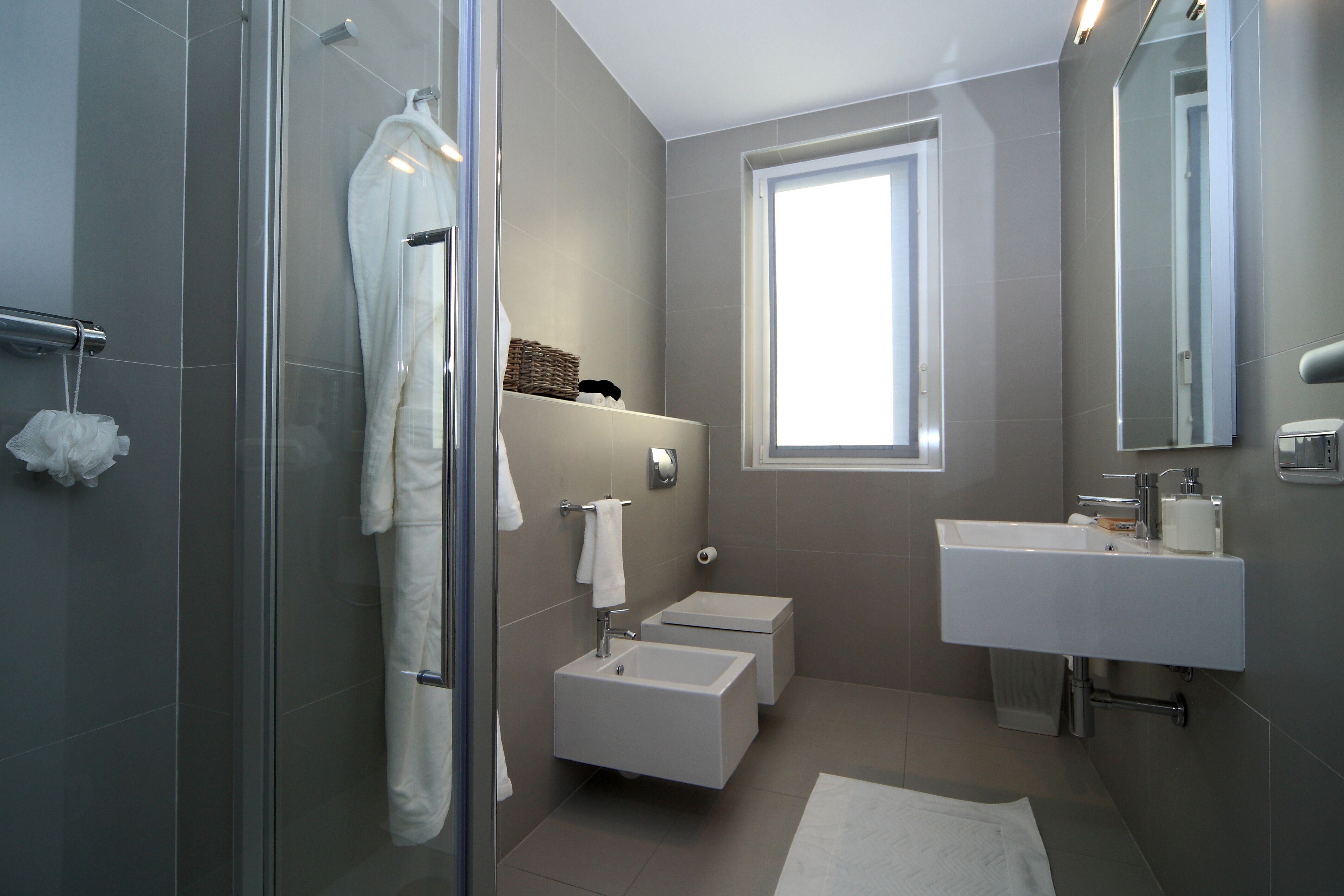 A modern bathroom with a glass shower enclosure, a white sink, and a large mirror.