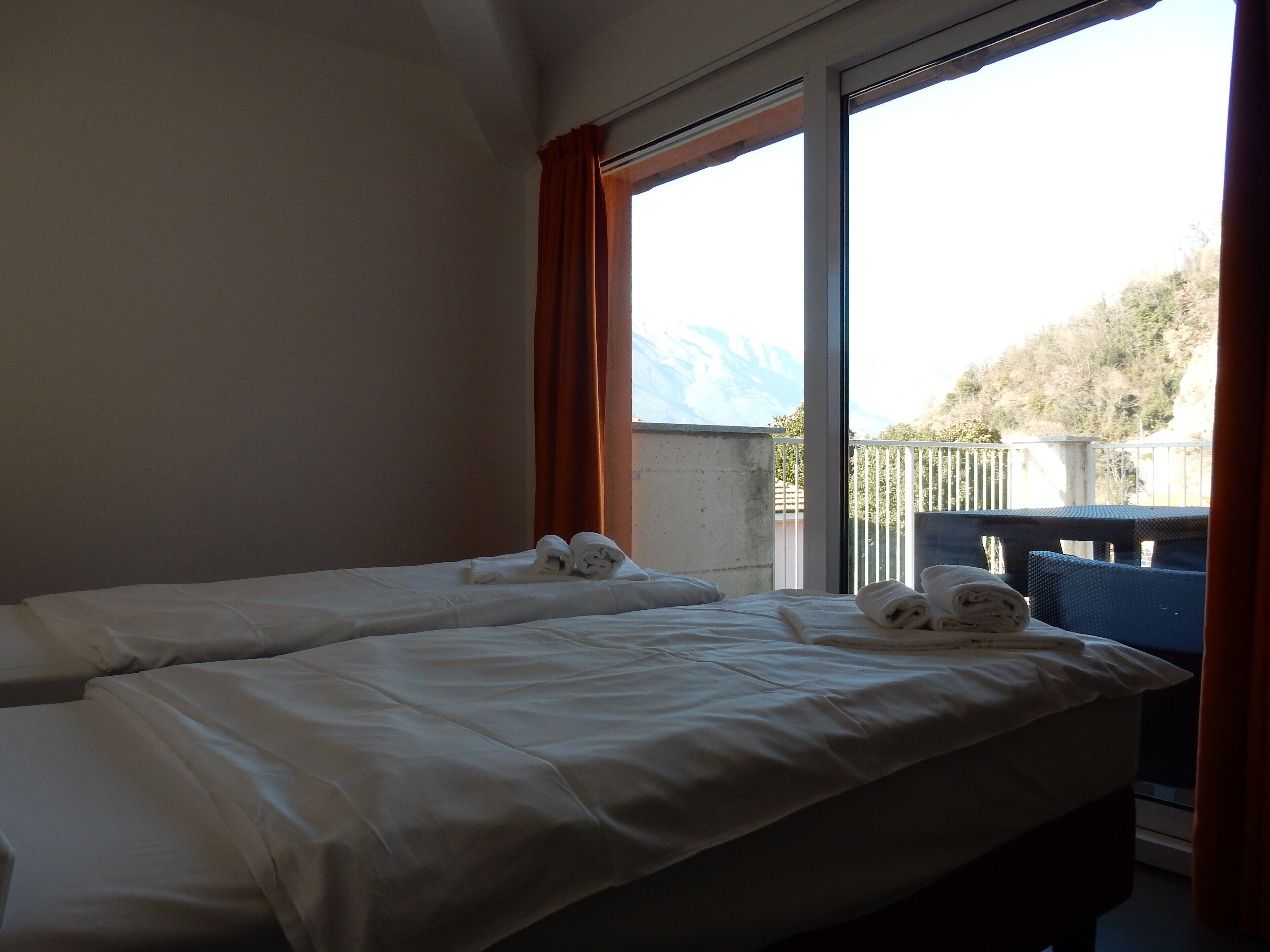 Ein Hotelzimmer mit zwei Betten, einem großen Fenster und Blick ins Freie.