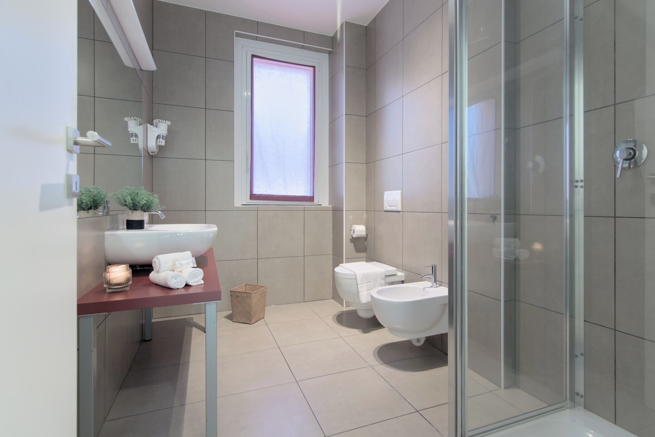 Un baño moderno con cabina de ducha de vidrio, un lavamanos grande y un bidé.
