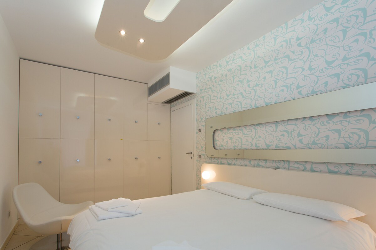 A modern bedroom with a bed, a chair, and a wardrobe.