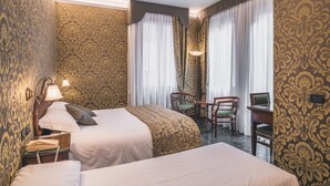 A hotel room with two beds, a desk with a chair, a lamp, and a telephone. - Hotel Al Malcanton (Venice)