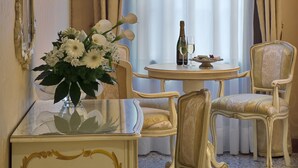A room with a round table, two chairs, a vase with flowers, a bottle, and a glass on the table. - Hotel Al Malcanton (Venice)
