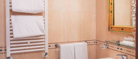 Un baño con bidé, dos lavamanos, un espejo y un toallero con toallas.