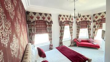 Un dormitorio con una cama grande, un sofá rojo y una ventana con cortinas.