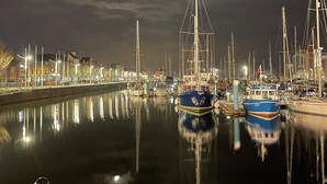 Una marina nocturna con barcos amarrados a lo largo de una vía fluvial tranquila, iluminada por luces ambientales.