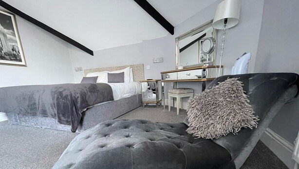 Un dormitorio moderno con una cama grande, una mesita de noche, una silla y un espejo.