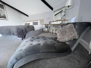 A modern bedroom with a large bed, a bedside table, a chair, and a mirror.