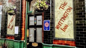 El Whittington Inn, con una fachada tradicional, una puerta negra y señalización que indica un bar y una sala acogedora.