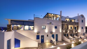 Un hotel moderno con terraza en la azotea, varios balcones y fachada de piedra.