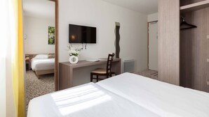 Una habitación de hotel con una cama, un escritorio con una silla, un televisor y un armario.
