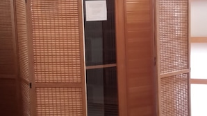 Una habitación de madera con una puerta corredera, un cartel en la pared y una planta en la esquina.