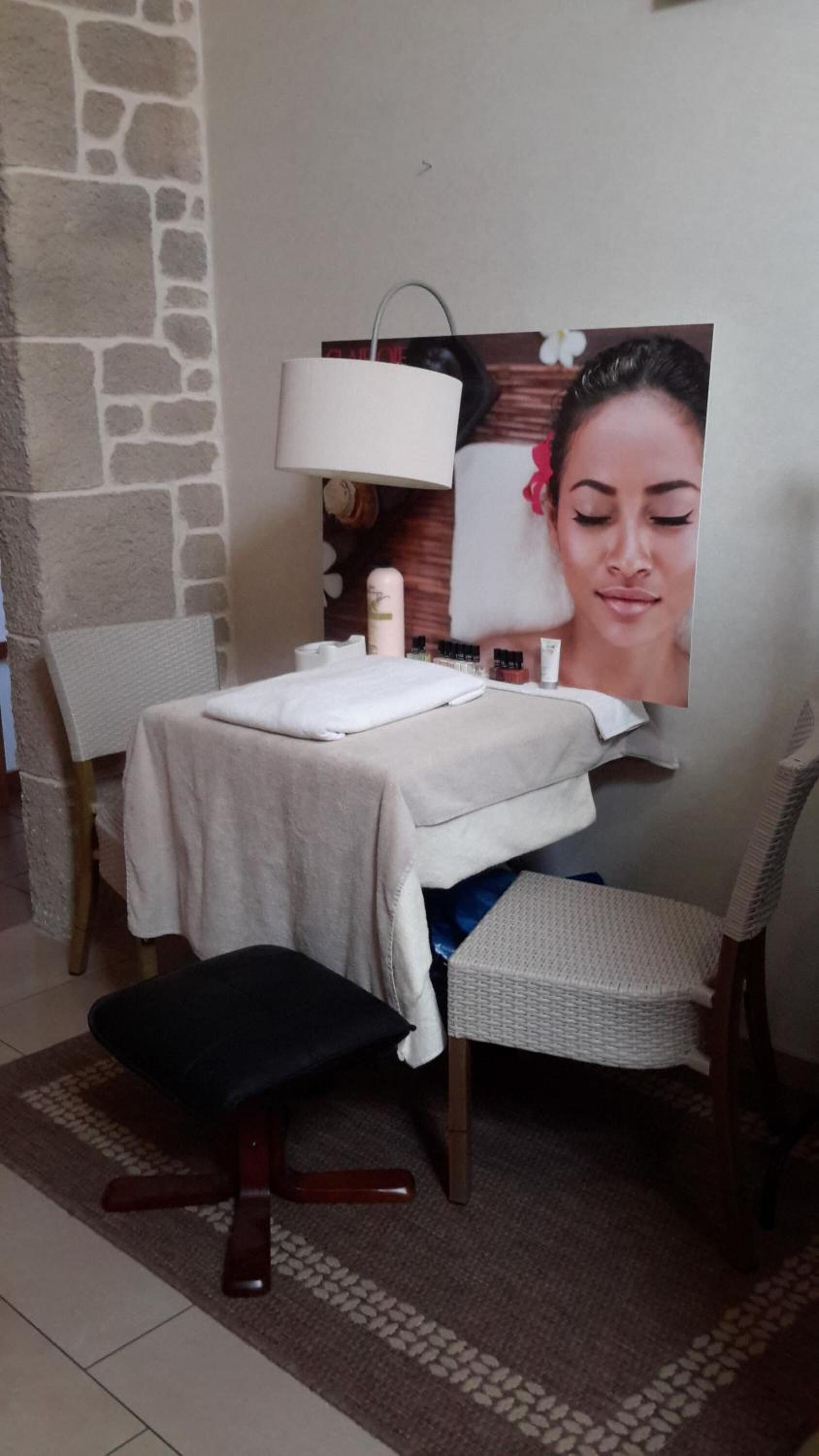 Un cuarto de spa con una camilla de masaje, una silla, una lámpara y un cartel en la pared.