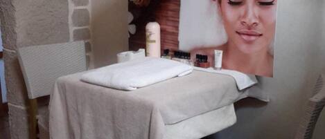 Un cuarto de spa con una camilla de masaje, una silla, una lámpara y un cartel en la pared.