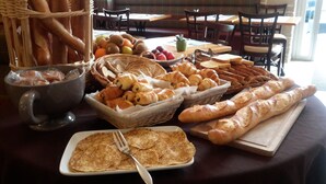 Un bufé de desayuno con pan, bollería y frutas.