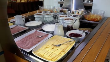 A buffet with various food items including meats, cheeses, and condiments.