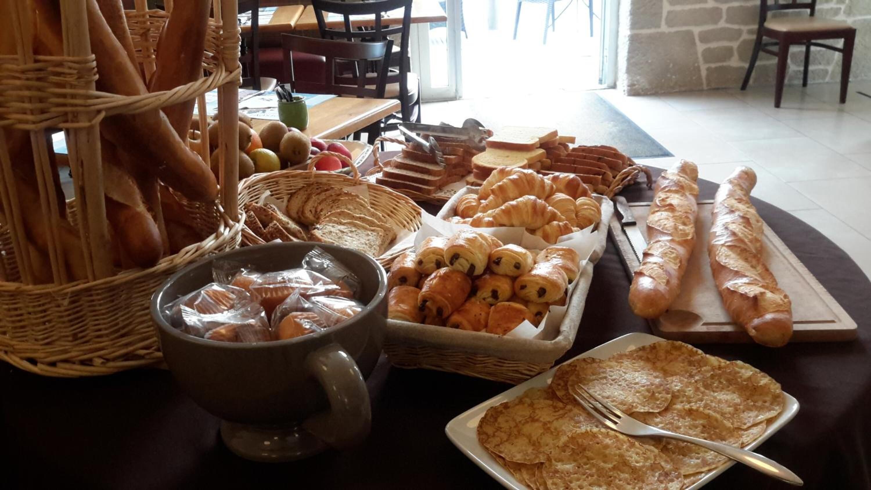A breakfast buffet with bread, croissants, and pastries.